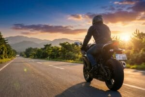 夕焼けの一般道を走行する大型バイクのライダー。バイク免許合宿で免許取得後の公道走行シーン。